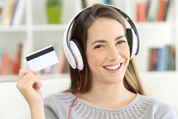 Girl listening to music and showing blank credit card
