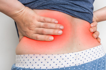 Woman with back pain touching her aching back