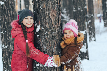 Happy children play in the winter in the woods