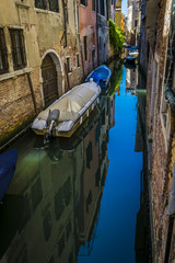 Fototapeta na wymiar Canals and historic buildings of Venice, Italy. Narrow canals, old houses, reflection on water on a summer day in Venice, Italy.
