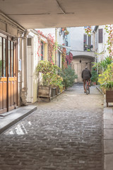 Paris, typical passage, small paved path, with a man on a bicycle
