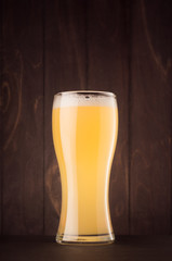 Beer glass with muddy weizen on dark wood board, vertical. Template for advertising, design, branding identity, restaurant menu, cover.