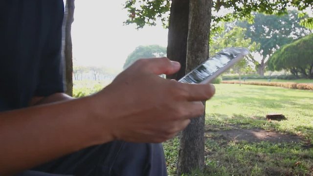 Men used finger touching touch screen play smartphone check email on display in garden
