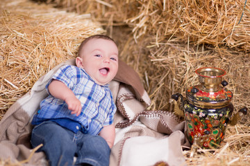 Rustic baby child boy posing on mountain of village dry straw wearing blue jeans and t-shirt happy...