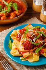 Italian pasta pappardelle with meatballs in tomato sauce.