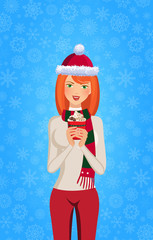 Christmas and new year illustration of cute ginger girl in santa hat and striped scarf holding red cup with hot drink isolated on blue snowy background. Vector illustration, clip art.
