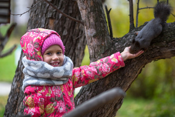 Little girl with hand feeding a squirrel in the Park.