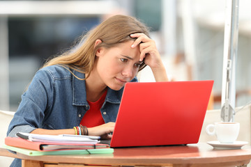 Fototapeta na wymiar Worried student searching on line in a laptop