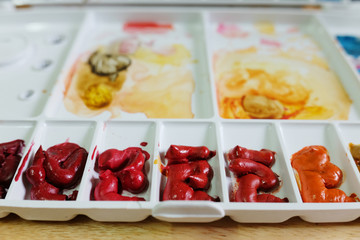 closeup palate of water color paint on wooden black ground