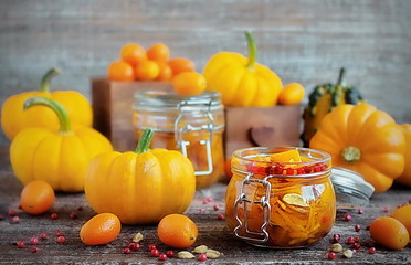Homemade pumpkin pickle in a glass container on a wooden table. Sweet an sour squash vegetables