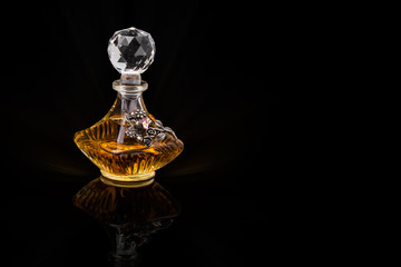 Close Up Shot Of Traditional Luxury Arabic Oud Oil Perfume In A Beautiful Handmade Clear Crystal Glass Jar Bottle and Glass Dropper Isolated On Black Background Antique Style, Text Space