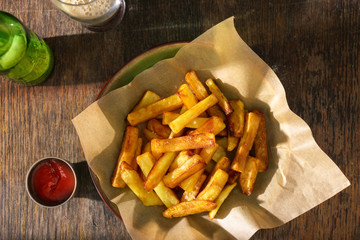 French fries with ketchup and dark beer on wooden table
