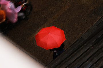someone with red umbrella in rain on street