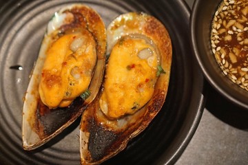 roasted spicy mussel on black plate with japan style seafood sauce