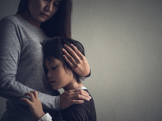 Sad little boy being hugged by his mother at home. Parenthood, Love and togetherness concept.