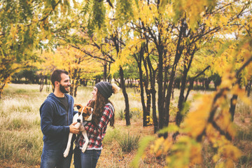 Cute couple playing with their dog in the fall leaves