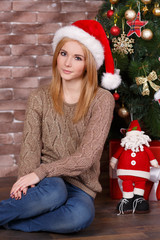 Amazing beautiful face lady girl with perfect skin and blond hairs posing for christmas holidays close to new year green pine tree and presents in studio