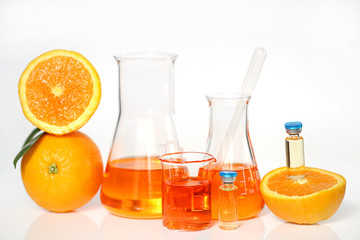 Serum with vitamin C in ampoules.  vitamin c in  laboratory bottles, orange in a cut on a white background. Vitamins concept. Organic vegan cosmetics for beauty and health. 