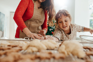 Little girl helping her mother in making cookies for  Christmas.