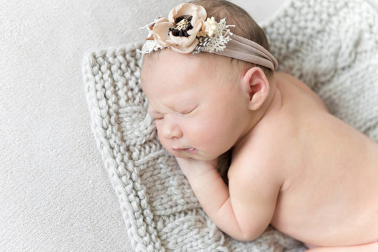 Close-up photo of newborn baby girl sleeping on a knitted blanket.