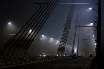 Fototapeta na wymiar Bridge and traffic under lanterns in the mist during night.