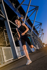 Fototapeta na wymiar sporty woman running outdoor beside the stadium. Fit female fitness runner jogging in the city
