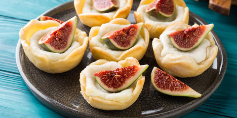 Tartlets with ricotta and figs on green wooden table. Mini treats