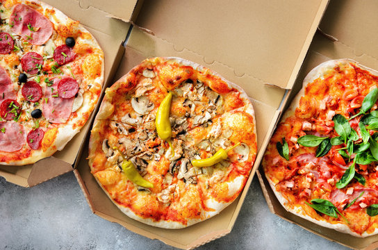 Fresh pizza in delivery box on grey concrete background. Top view, copy space