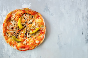 Fresh italian pizza with mushrooms, ham, tomatoes, cheese, olive, pepper on grey concrete background. Copy space. Top view.