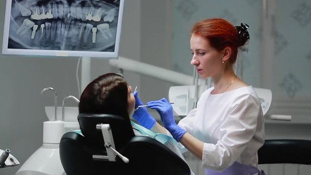 The dentist completes his work with a patient. Removes Bor machine and gives a girl a mirror to assess the work. The girl looks at your teeth and thanked the dentist.