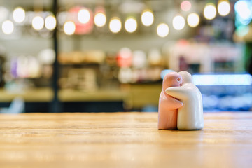 Ceramic couple dolls hugging on the floor with decorative indoor string lights bulb  background.