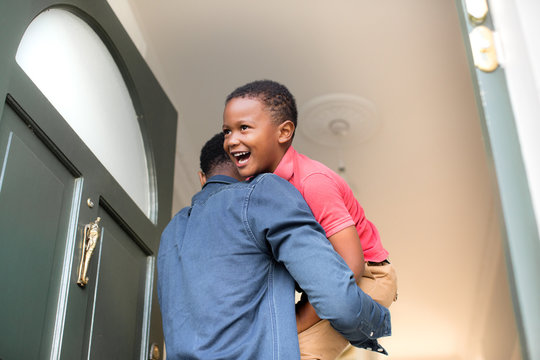 Dad carrying son into family home