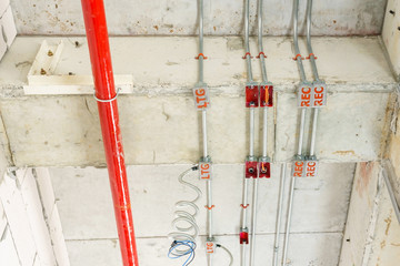 Metal pipes in Construction and fire sprinkler on red pipe are hanging from ceiling interior