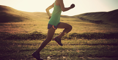 young fitness woman runner running on grassland trail