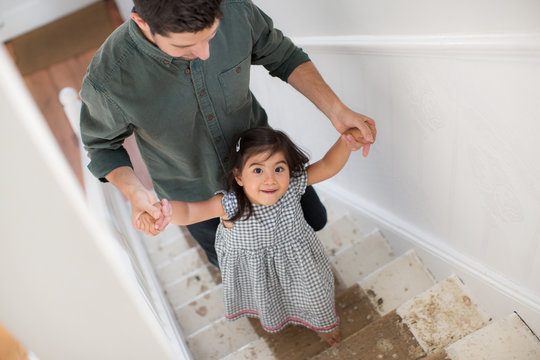 Father Helping Daughter Walk Up Stairs