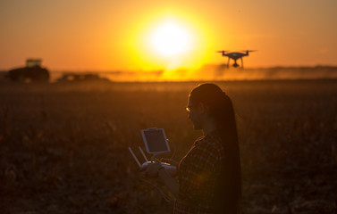 Woman navigating drone above farmland