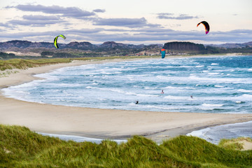 Kitesurfing men in action on stormy sunset evening at Brusand Beach, Norway.