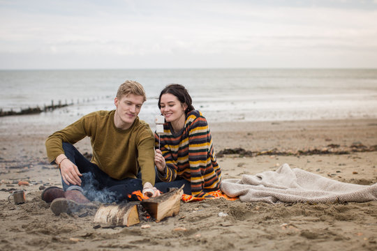 Young couple toasting marshmallows on camp fire