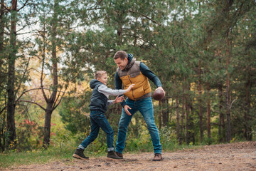 Naklejka na ściany i meble father and son playing with ball in forest