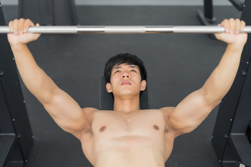 Naklejka premium Fitness man in training showing exercises with barbells in gym
