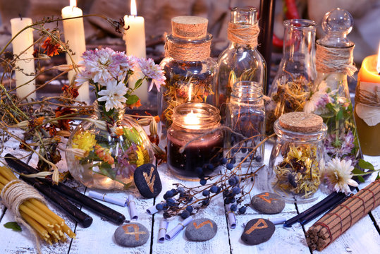 Glass bottles, candles, runes and magic objects on witch table