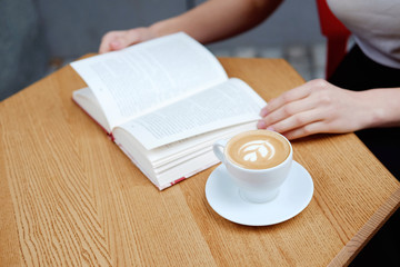 Girl reading in cafe and drinking cappuccino