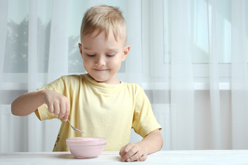 A small boy eats yogurt
