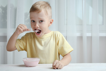 A small boy eats yogurt