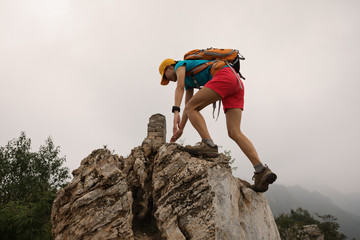 successful woman climber climbing rock on the top of mountain