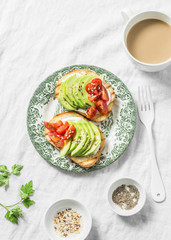 Avocado, soft cheese, cherry tomatoes sandwich and tea with milk on a light background, top view. Healthy snack, breakfast