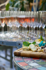 Different kinds of cheeses on wooden board, color table, wineglasses, vertical
