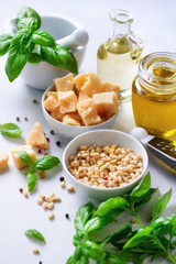 Ingredients for homemade pesto - basil, lemon, parmesan, pine nuts, garlic, olive oil and salt on white concrete background. Top view, flat lay, copyspace. Banner