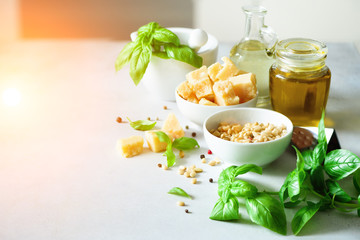 Ingredients for homemade pesto - basil, lemon, parmesan, pine nuts, garlic, olive oil and salt on rustic wooden background. Top view, flat lay, copyspace. Sunny morning