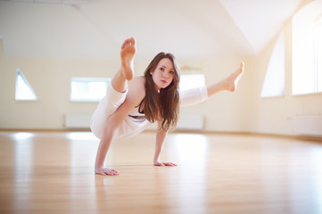 Naklejka na ściany i meble Beautiful woman practices handstand yoga asana Tittibhasana - firefly pose in the yoga studio